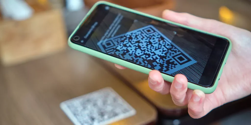 Closeup of guest hand ordering meal in restaurant while scanning qr code with mobile phone for online menu.