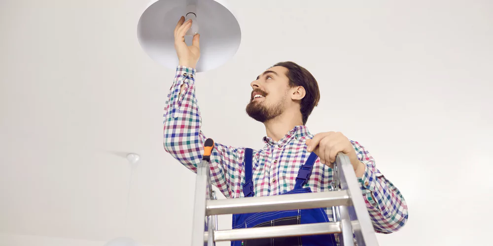 restaurant staff replacing light bulb with LED to save on restaurant electricity costs