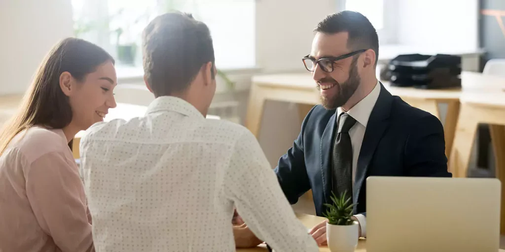 Friendly lawyer or financial advisor in suit consulting young couple, smiling investment broker or bank worker making loan offer, giving legal advice, selling insurance or real estate to customers