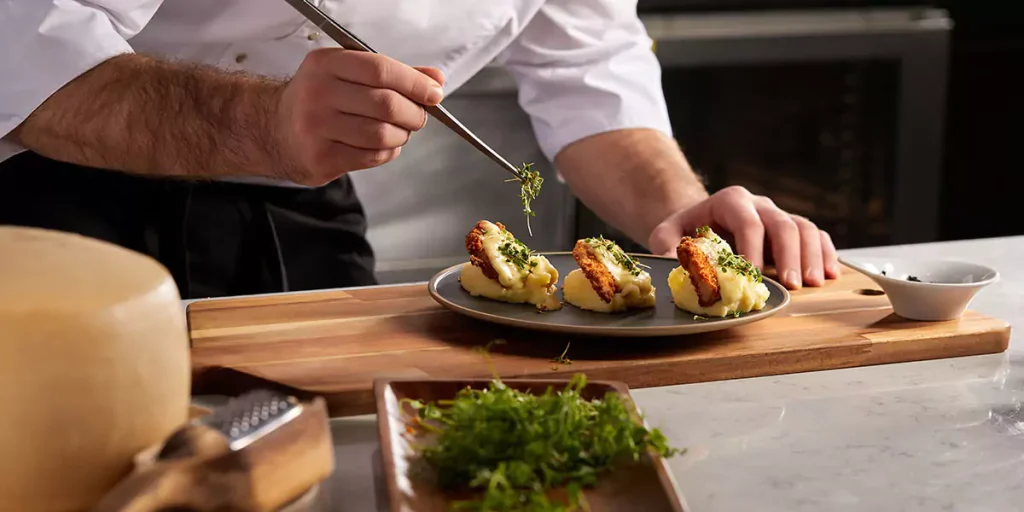 Cropped photo Close-up hands of male cook adding greens finishing dish, decorating meal in the end. gastronomy, food, nutrition, cafe concept