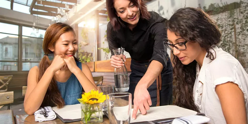 Waitress server helping client patron customer with menu order on sunny patio